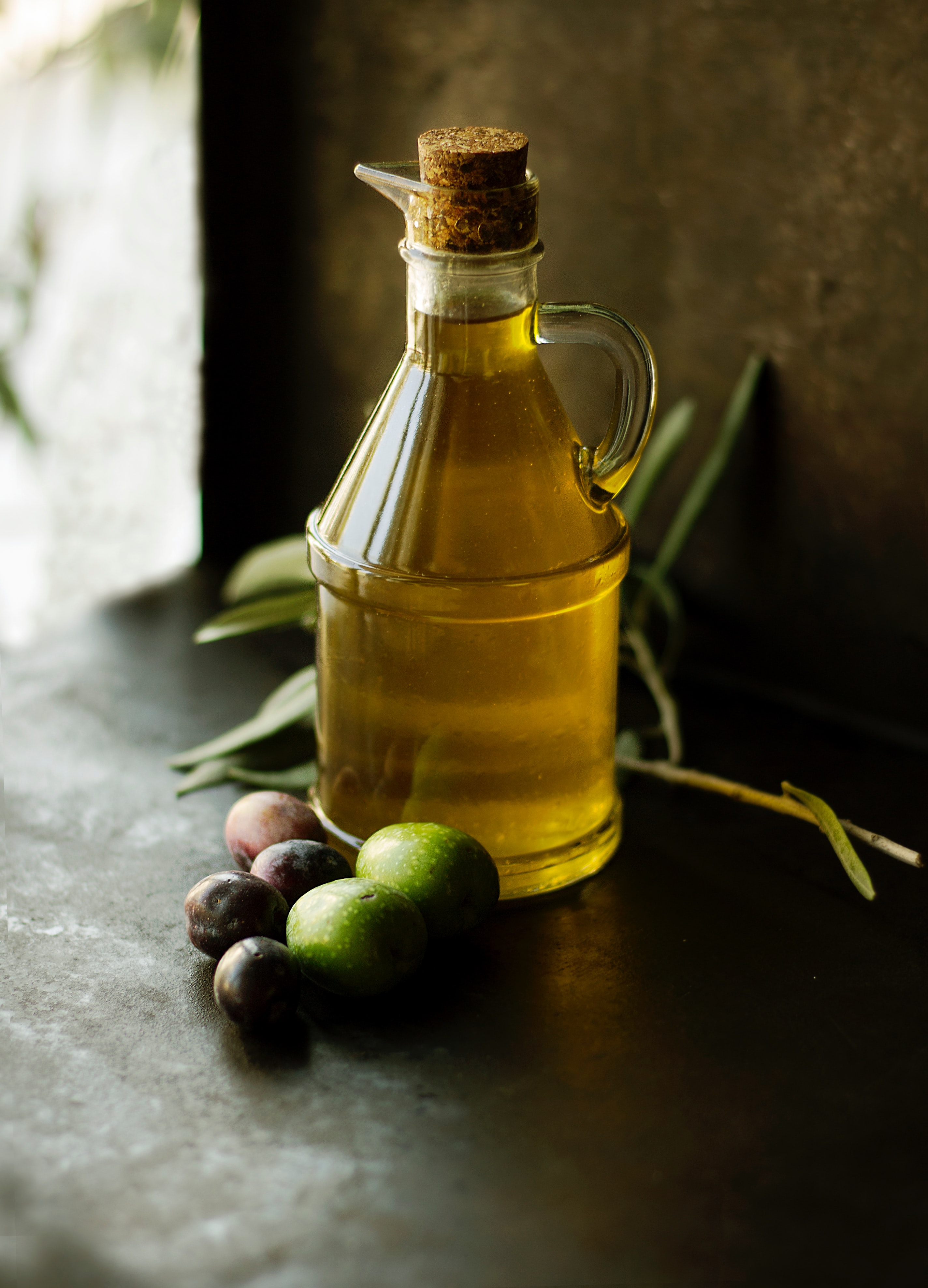 source of glycerin for skin, olive oil in a bottle with olive sitting next to it 